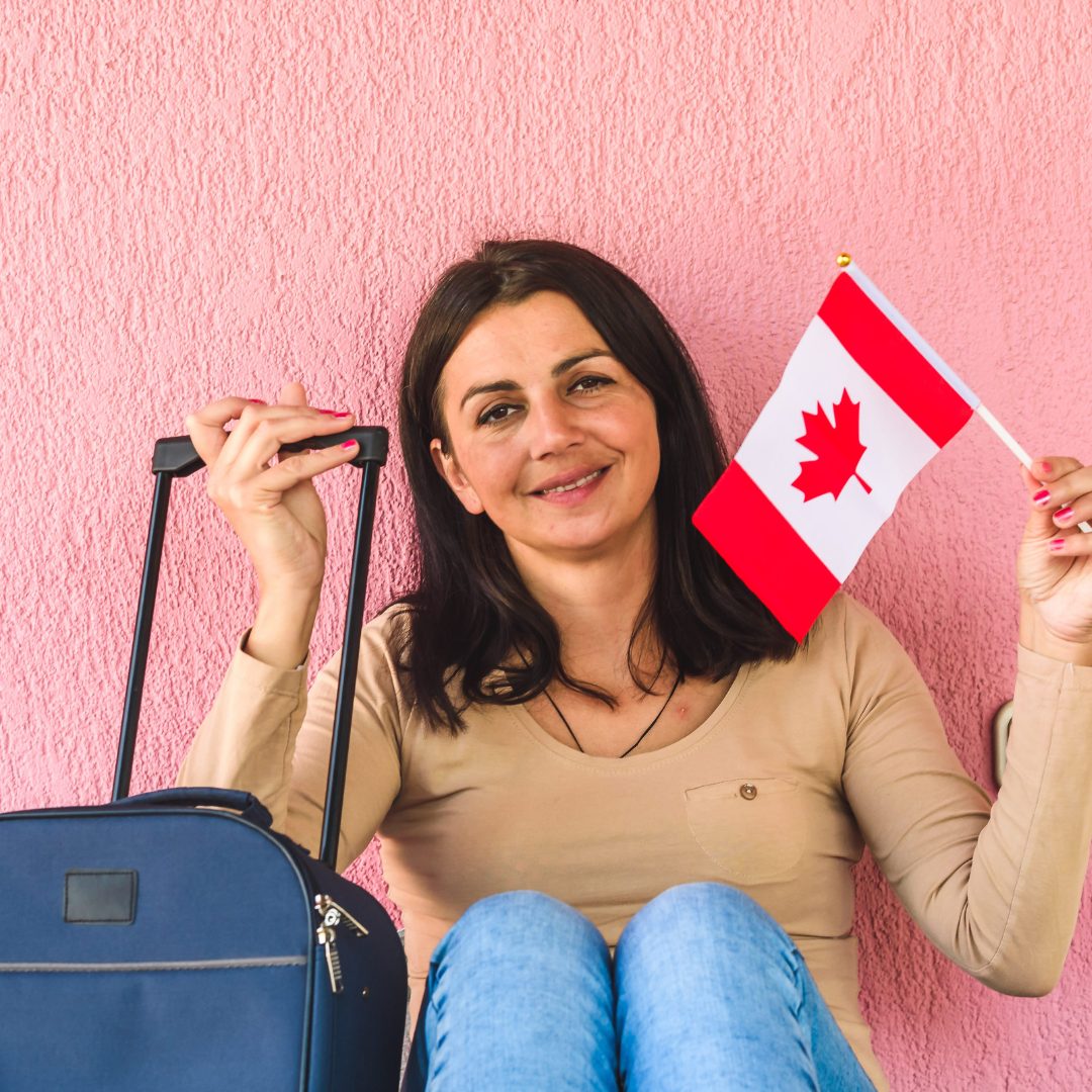 women with a Canada flag and a suitcase excited to move to Canada