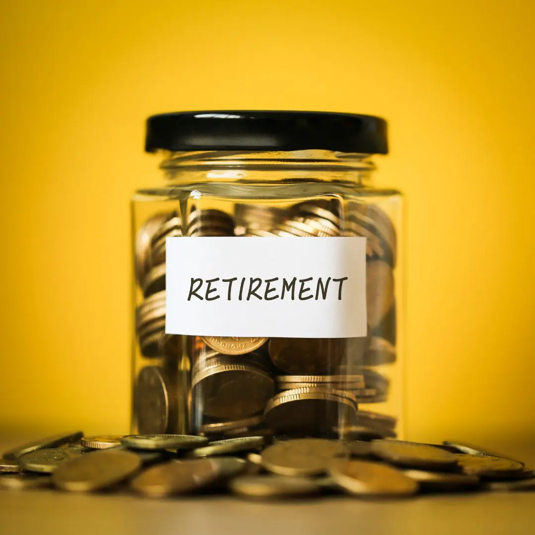 glass mason jar filled with coin to indicate retirement savings. the jar has a label stuck to the front saying 'retirement'.